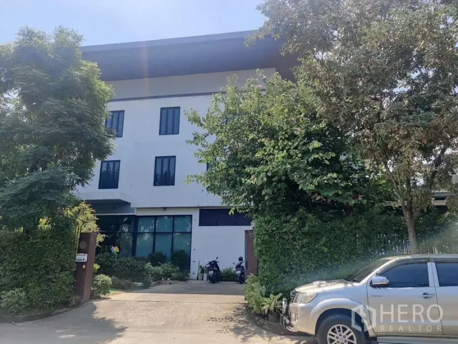 Home Office for sale - Front facade of a multi-storey home office with driveway and lush trees.