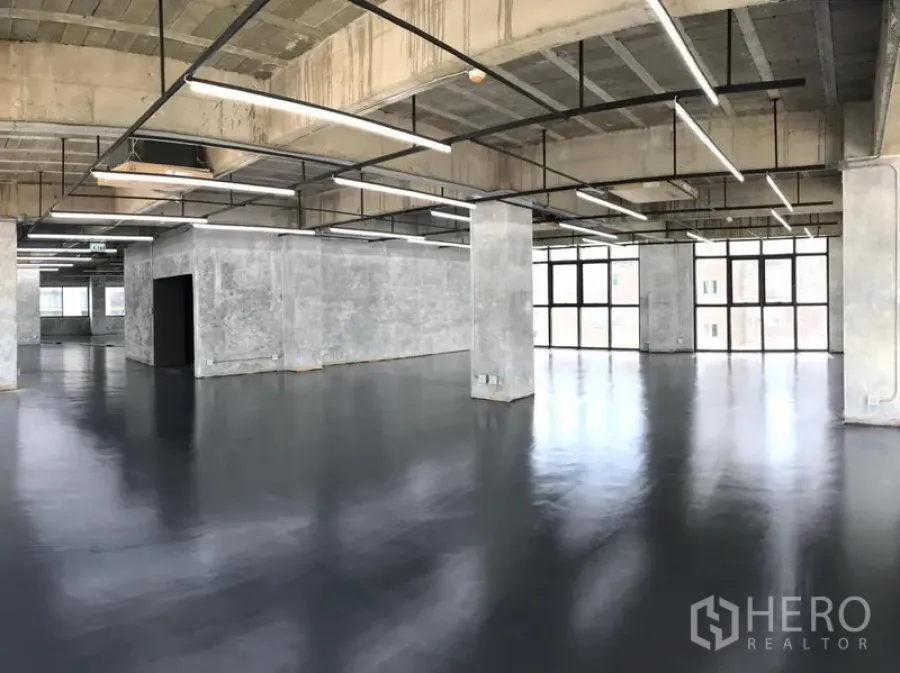 办公空间 出租在Khlong Toei, Bangkok - 开放式阁楼风办公室，外露混凝土天花、线性LED灯、黑色亮面地坪与整面窗。