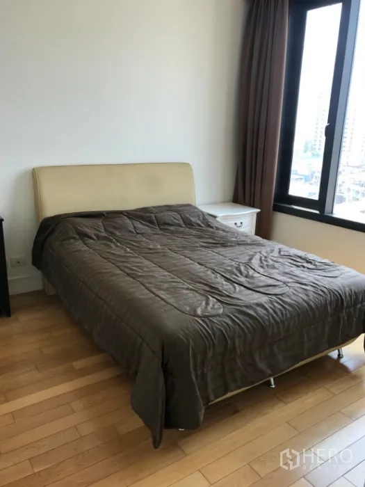 Condominium for rent or sale in Khlong Toei, Bangkok - Bedroom with queen bed, wood floors and large window offering city views.