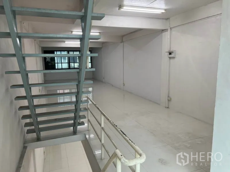 Shophouse for rent in Bang Rak, Bangkok - View from stair landing across a long open-plan level with windows at the far end.
