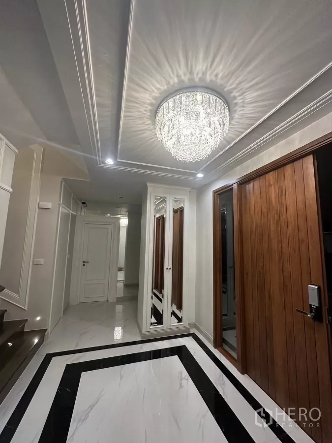 Detached House for rent or sale in Bang Kapi, Bangkok - Grand entry hall with crystal chandelier, wood doors and black-and-white marble flooring.