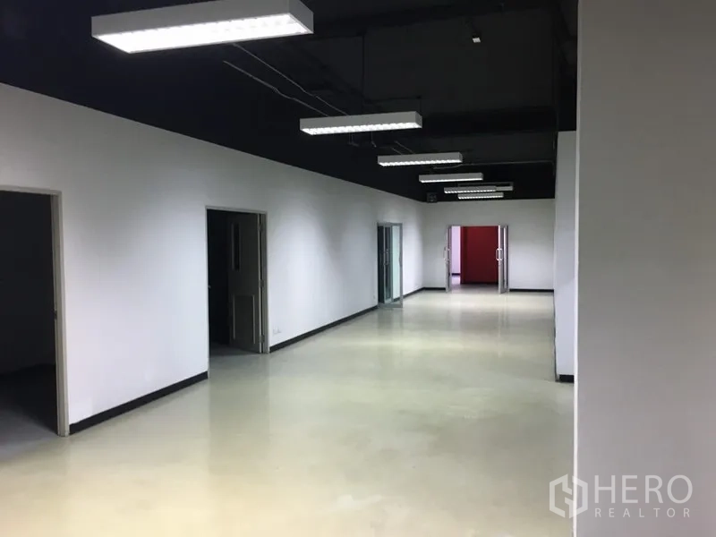 Office Space for rent in Huai Khwang, Bangkok - Wide corridor with multiple office rooms and glass doors under suspended lights.