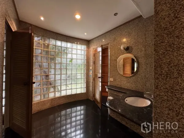 Townhouse for rent in Khlong Toei, Bangkok - Spacious bathroom featuring a curved glass-block window, granite walls and a vanity sink.