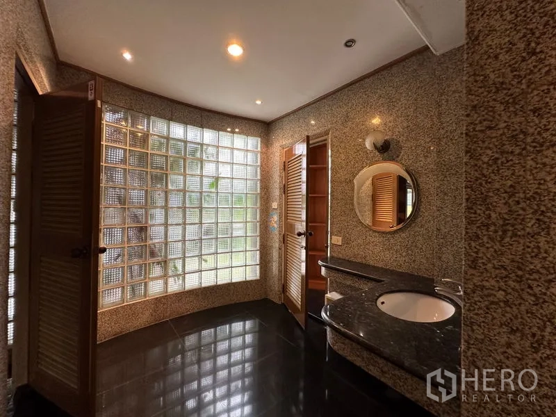 Townhouse for rent in Khlong Toei, Bangkok - Spacious bathroom featuring a curved glass-block window, granite walls and a vanity sink.
