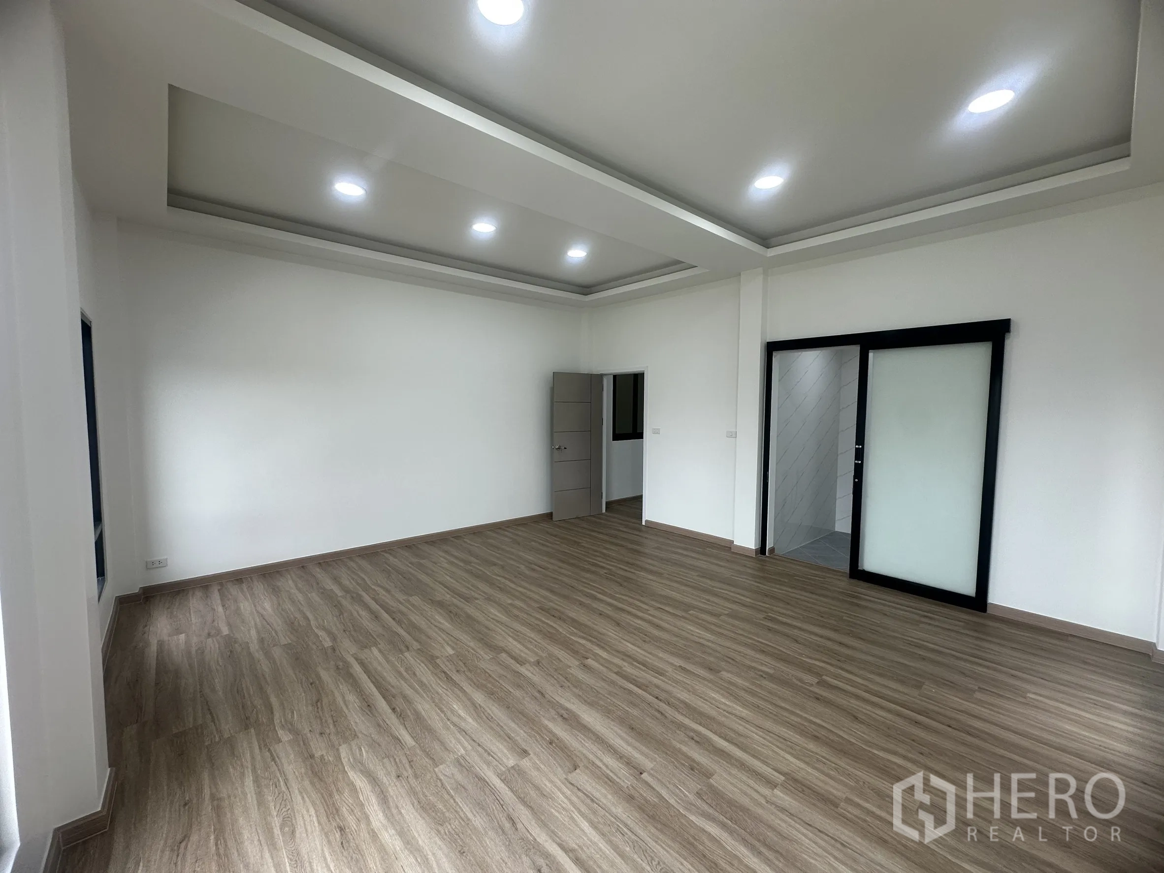 Warehouse for sale in Khlong Luang, Pathum Thani - Spacious office or meeting room with cove ceiling, sliding door to bathroom and wood floors.