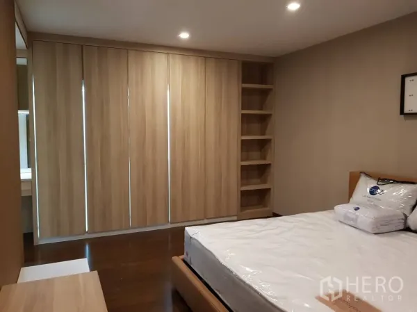 Condominium for rent or sale in Pathum Wan, Bangkok - Spacious bedroom with wood flooring, large built-in wardrobes, and shelving for storage.