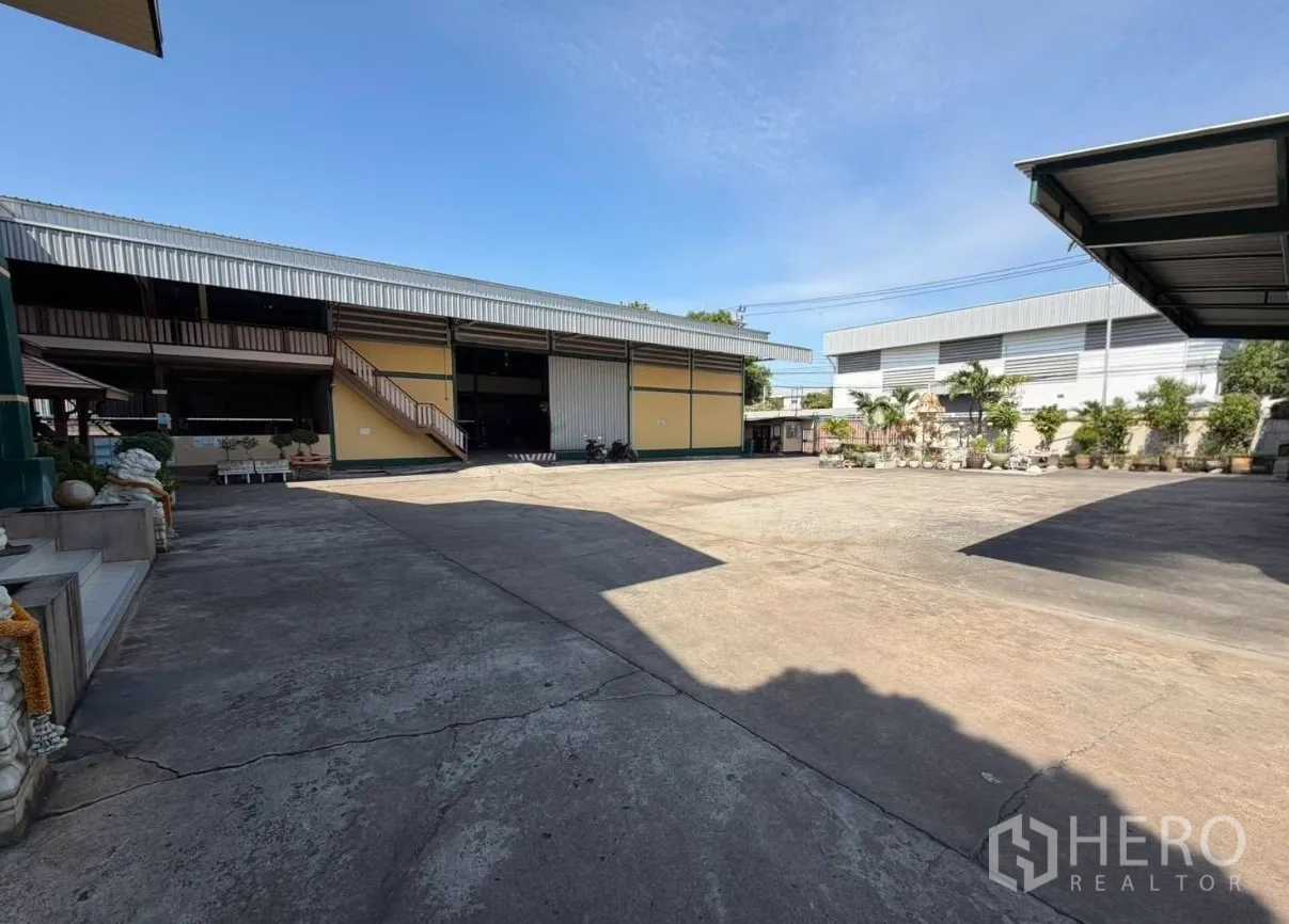 Factory for rent in Bang Phli, Samut Prakan - Expansive hardstand in front of yellow warehouse building with external stairs.