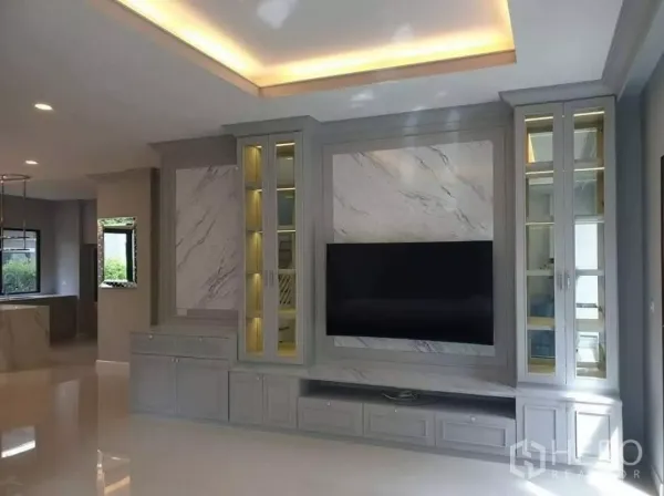 Detached House for rent or sale in Prawet, Bangkok - Bright living room with marble-feature TV wall and built-in glass cabinets