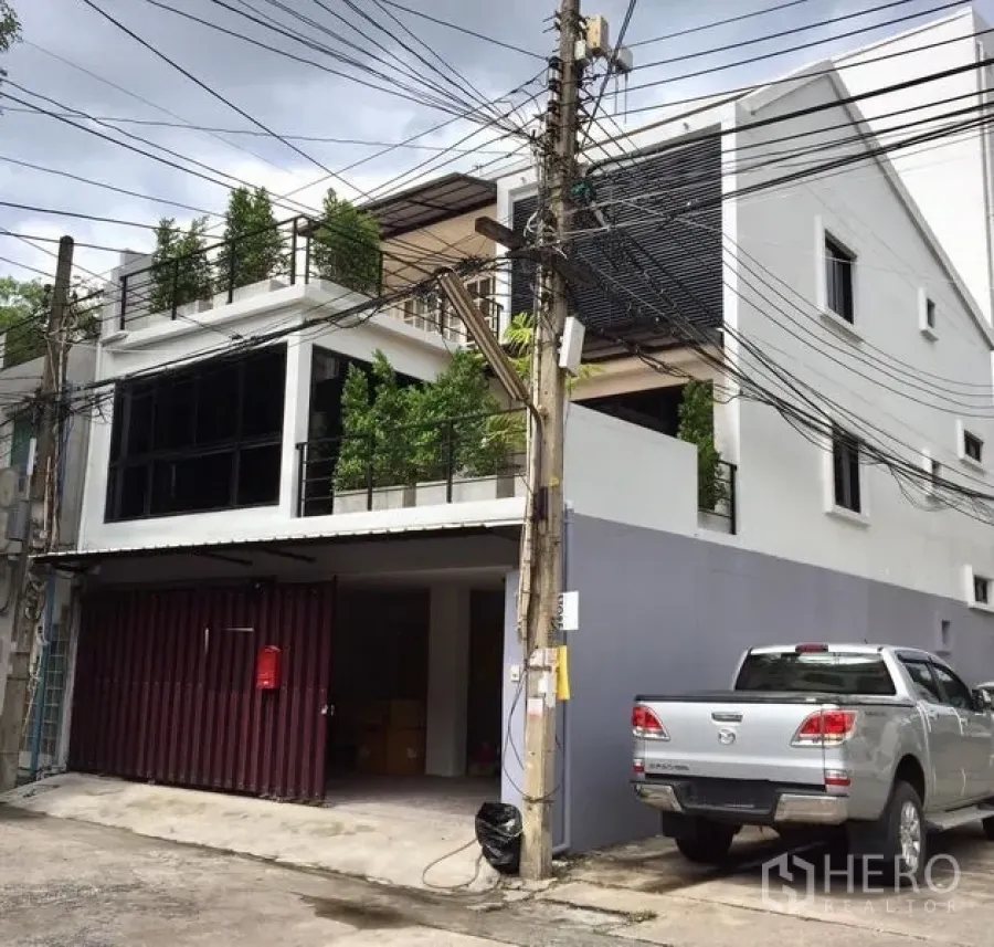Townhouse for rent in Khlong Toei, Bangkok - Modern three-storey townhouse exterior with greenery-lined balconies and covered parking in Ekkamai, Bangkok.