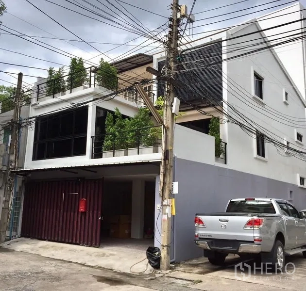 Townhouse for rent in Khlong Toei, Bangkok - Modern three-storey townhouse exterior with greenery-lined balconies and covered parking in Ekkamai, Bangkok.