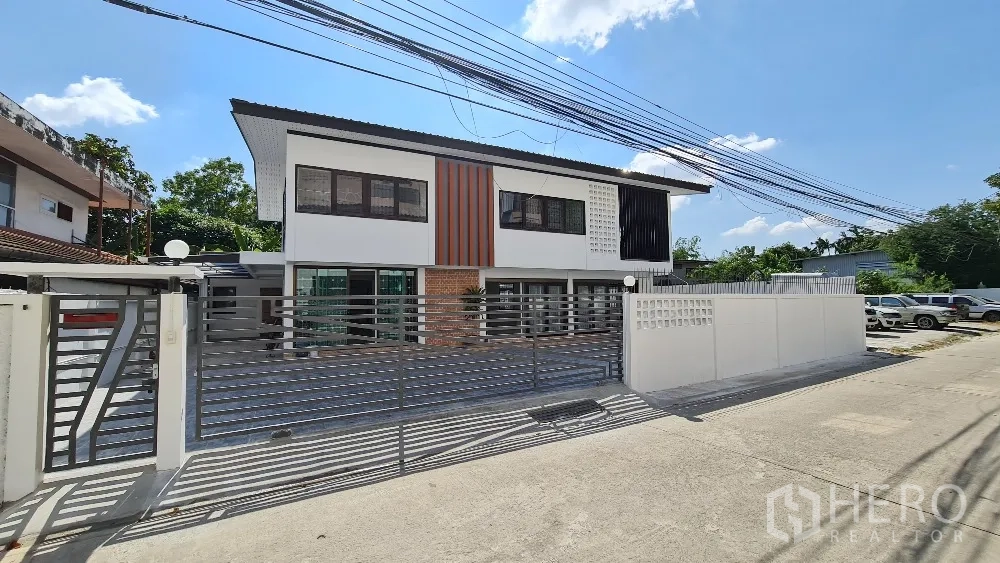 独栋房屋 for rent in Lat Phrao, Bangkok - 正立面配金属滑动大门与铺装车道和停车区。