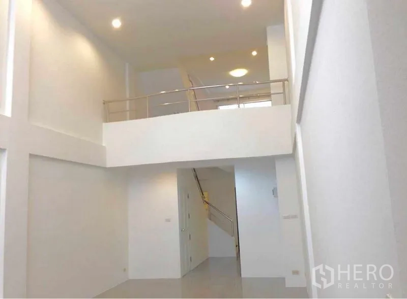 Home Office for rent in Wang Thonglang, Bangkok - Double-height lobby with white walls, mezzanine level and recessed lighting leading to a staircase.