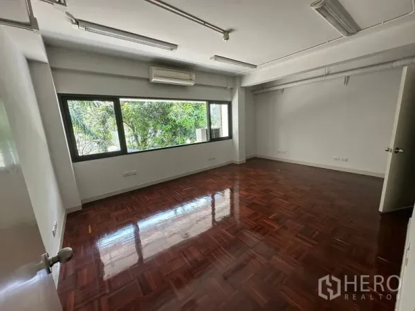 Office Space for rent - Bright office room with window views of trees and glossy wooden floors.