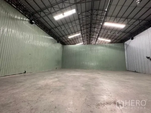 货栈 出租在Pak Kret, Nonthaburi - 开阔的仓储区域，波纹金属墙体、顶置照明与坚固地坪。