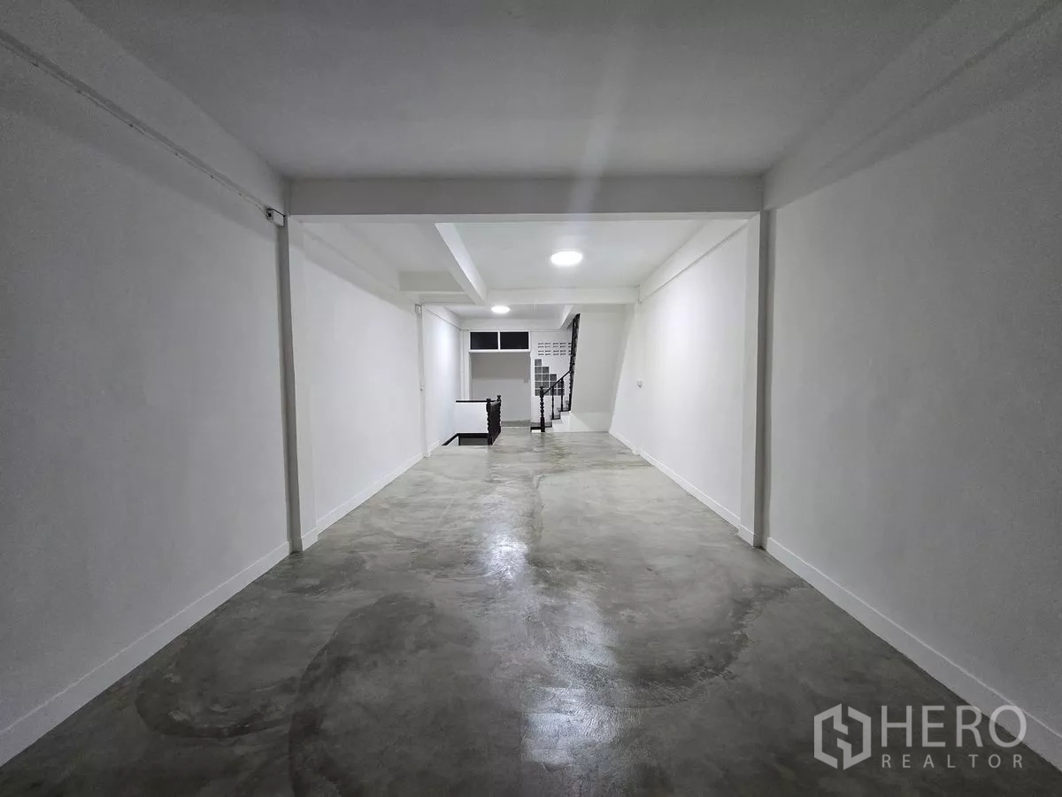 Shophouse for rent in Watthana, Bangkok - Upper level with polished concrete floor, white walls and a central stairwell.