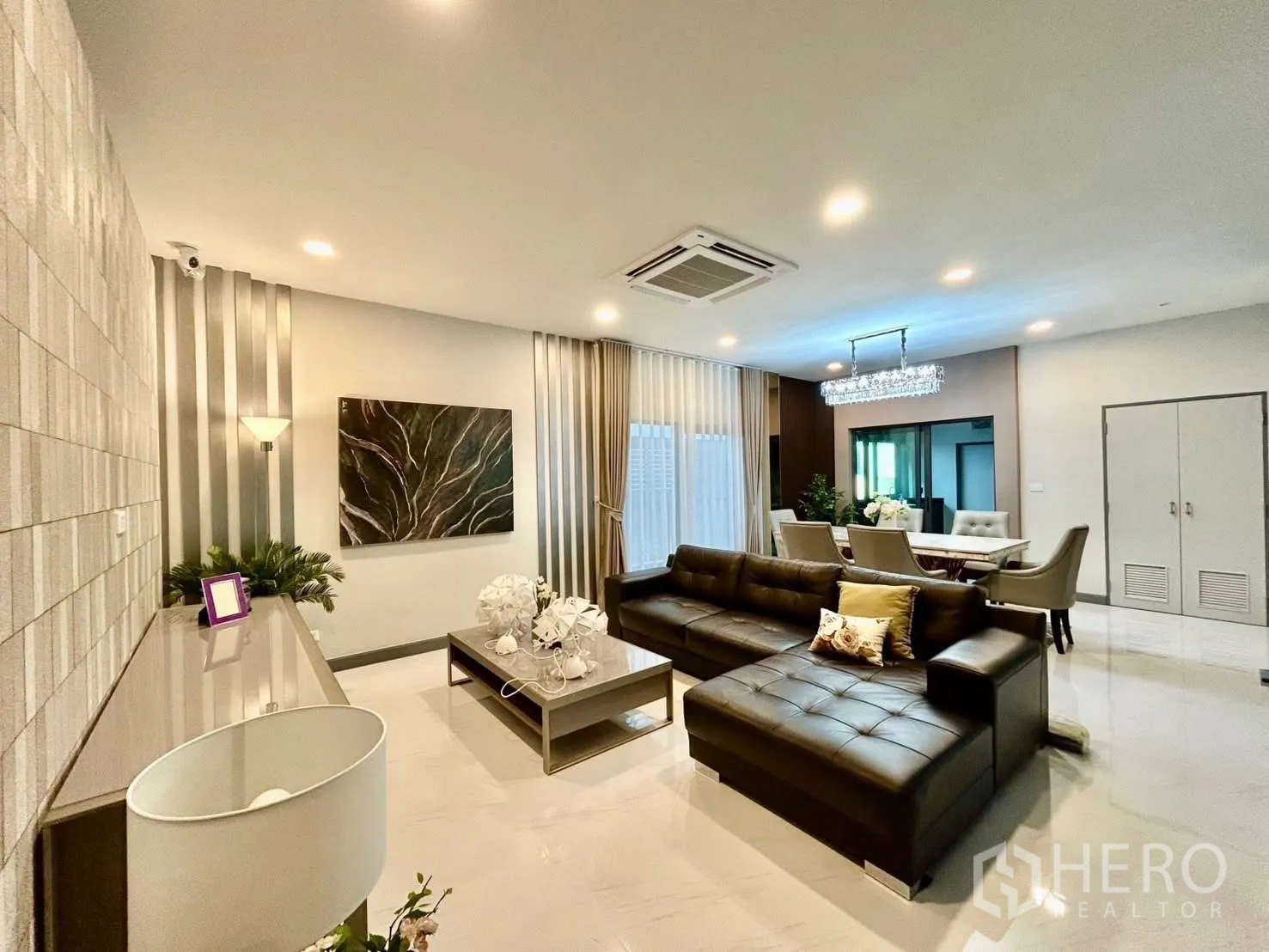 Detached House for rent in Bang Phli, Samut Prakan - Open-plan living and dining area with leather sectional sofa and chandelier.