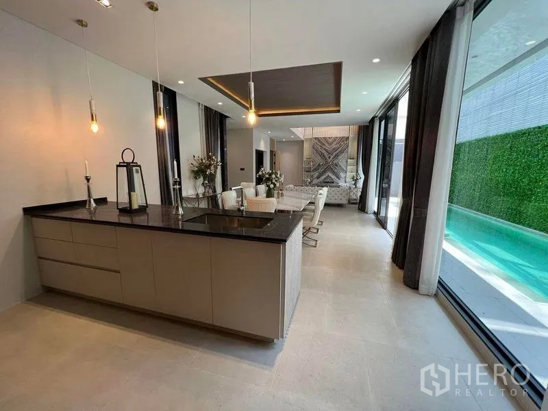 Detached House for sale in Suan Luang, Bangkok - Open-plan living and dining with an island kitchen, floor-to-ceiling glass and pool view in a modern Suan Luang house.