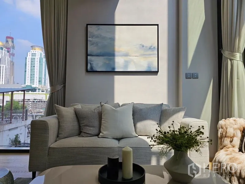Condominium for rent - Sofa by the window with wall art and cityscape beyond sheer curtains.