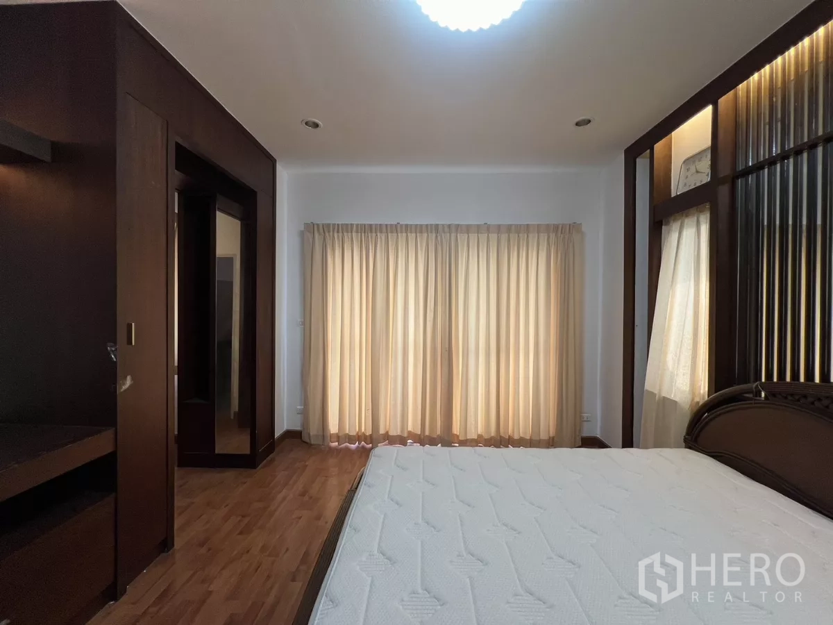 Detached House for rent in Bang Kapi, Bangkok - Master bedroom view toward full-height curtains and wardrobe.