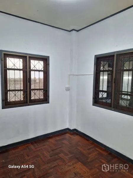 Detached House for rent in Bang Na, Bangkok - Bright bedroom corner with two windows and parquet floors.
