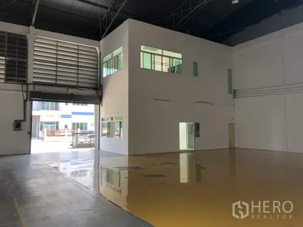 Factory for rent in Lam Luk Ka, Pathum Thani - High‑ceiling warehouse interior with mezzanine‑style office block and glossy epoxy floor.