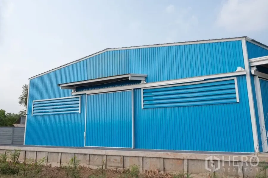 Warehouse for rent in Khlong Luang, Pathum Thani - Blue steel-clad warehouse exterior with large sliding door and ventilation louvers.