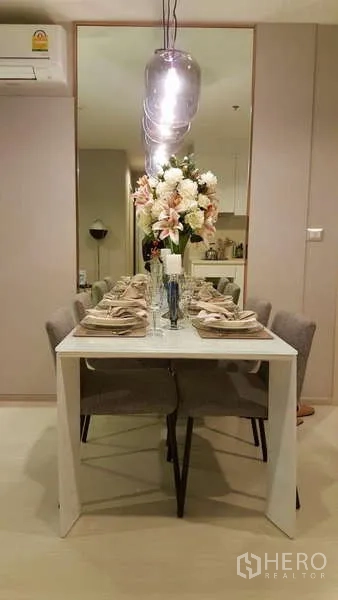 Condominium for rent in Khlong Toei, Bangkok - Close-up of dining table setting beneath three glass pendant lights and wall mirror.