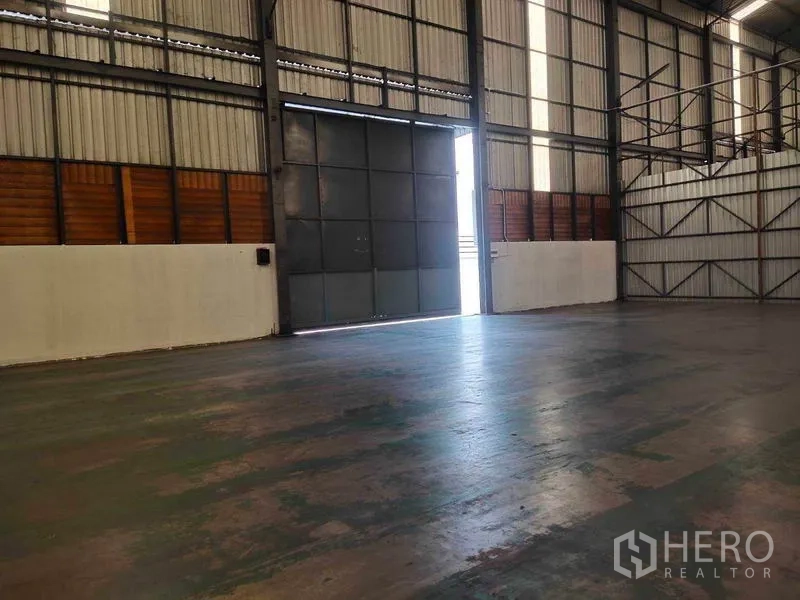 Warehouse for rent in Mueang Samut Sakhon, Samut Sakhon - Interior view toward wide sliding steel door allowing truck access to the floor.