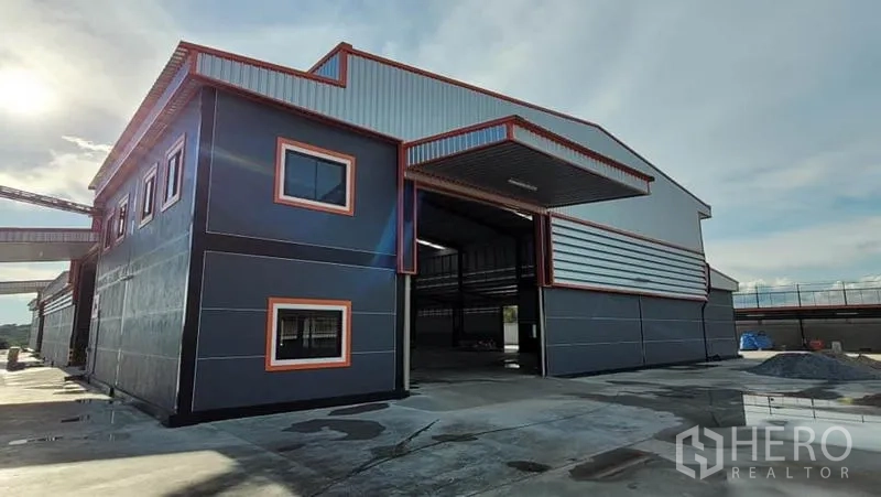 Factory for rent or sale in Phanat Nikhom, Chon Buri - Factory entrance with high clearance bay and attached two-storey office block with windows.