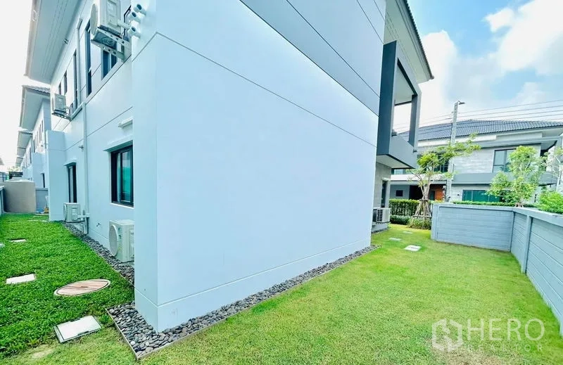 Detached House for rent - Side yard lawn wrapping the house with boundary wall and neat edging stones.
