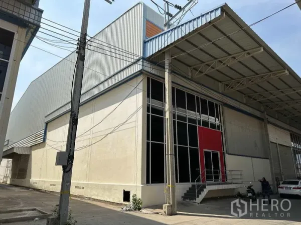Factory for rent in Bang Phli, Samut Prakan - Corner exterior view of the steel-clad factory with tall windows and sheltered loading area.