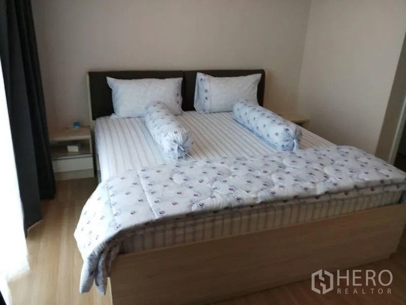 Townhouse for rent in Suan Luang, Bangkok - Spacious bedroom with a king bed, light wood flooring and bedside tables.