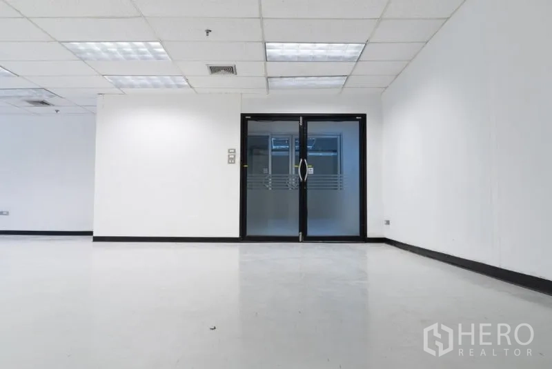 Office Space for rent in Ratchathewi, Bangkok - Double glass doors leading into a modern white office with a drop ceiling and bright lighting.
