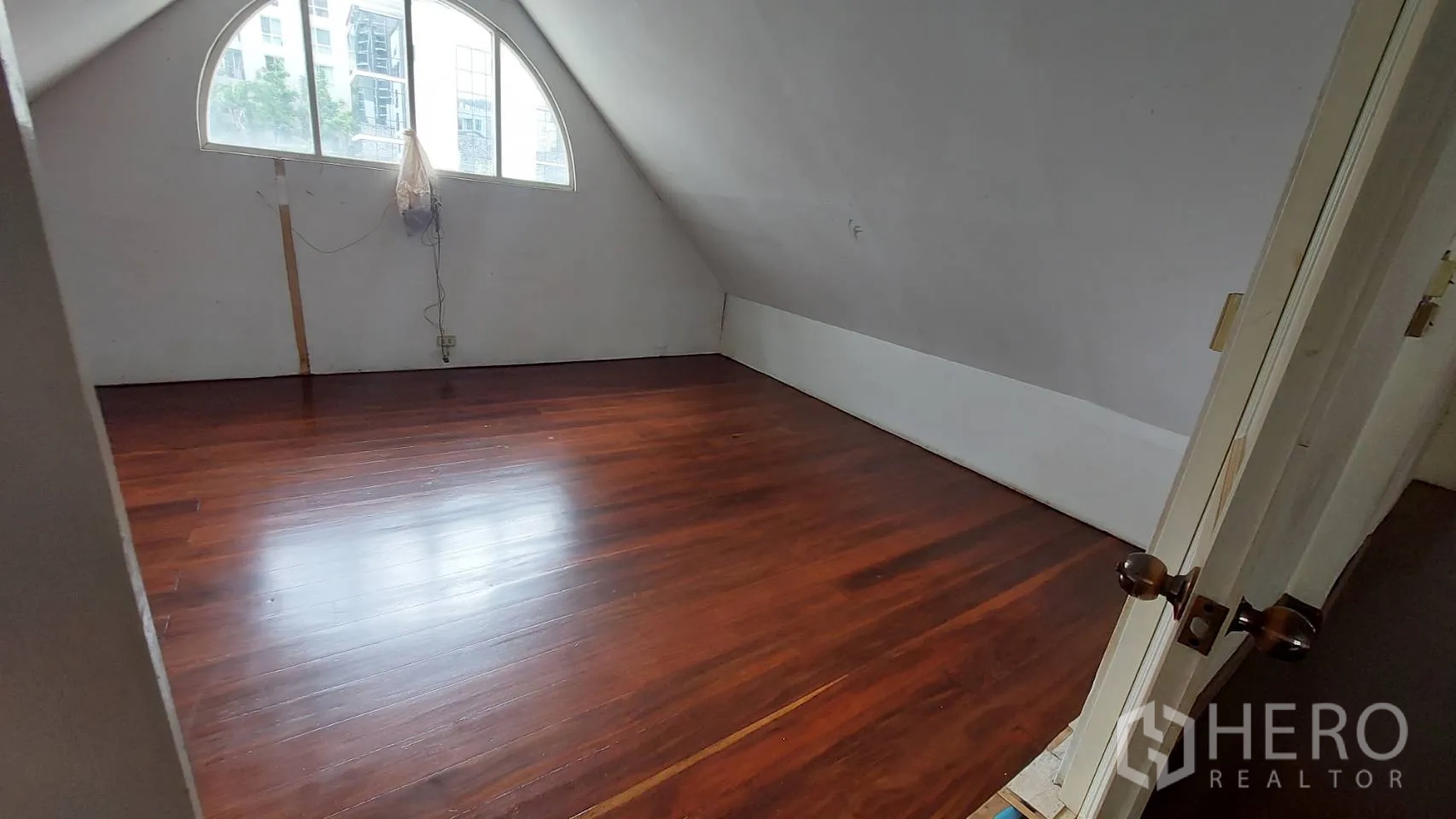 Office Space for rent in Watthana, Bangkok - Room with a sloped ceiling and arched window, polished wooden floor and city outlook, ideal for a private office or meeting room.