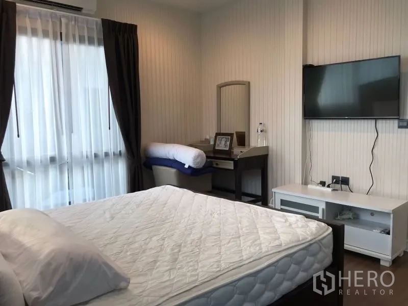 Detached House for rent in Bang Kapi, Bangkok - Bedroom with bed, wall-mounted TV and a dressing table by the window.