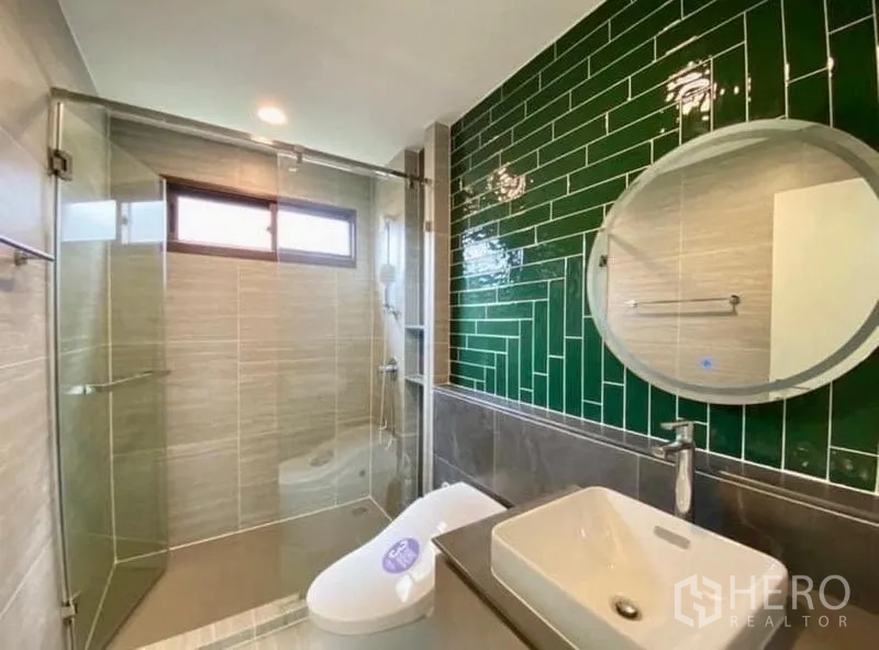 Detached House for sale in Bang Kapi, Bangkok - Modern bathroom with green subway-tile feature wall, glass shower enclosure and vanity.
