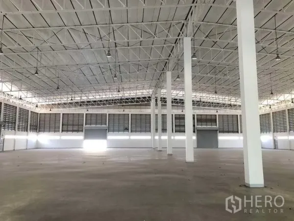 Factory for rent or sale in Phra Nakhon Si Ayutthaya - Vast production hall with high steel truss roof, white columns and smooth concrete floor.