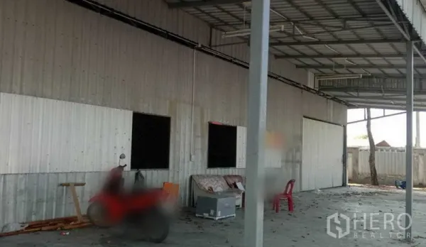 Warehouse for rent in Khlong Sam Wa, Bangkok - Side view of corrugated warehouse facade with roof canopy and open loading area on a concrete apron.