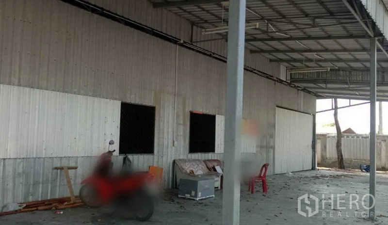Warehouse for rent in Khlong Sam Wa, Bangkok - Side view of corrugated warehouse facade with roof canopy and open loading area on a concrete apron.