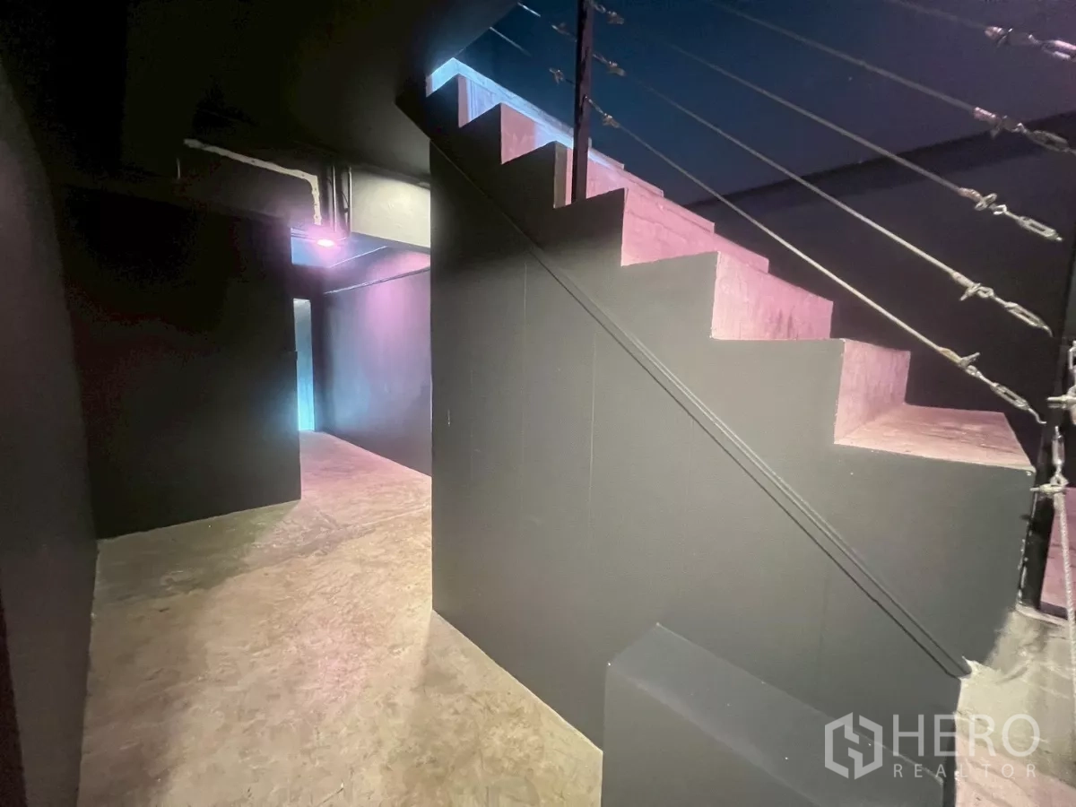Shophouse for rent in Watthana, Bangkok - Internal staircase with dark walls leading to upper levels under moody lighting.