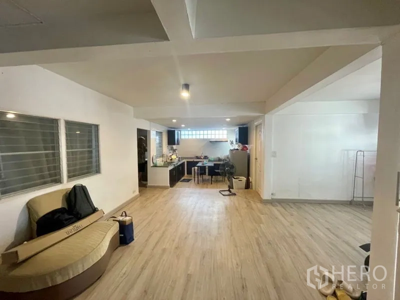 Townhouse for rent in Din Daeng, Bangkok - Open-plan living and dining area with wood-look flooring leading to a fitted kitchen.