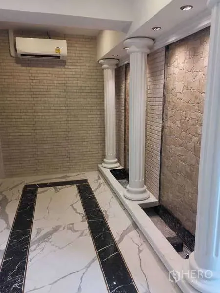 Retail Space for rent - Room with white columns, textured stone wall and marble flooring.