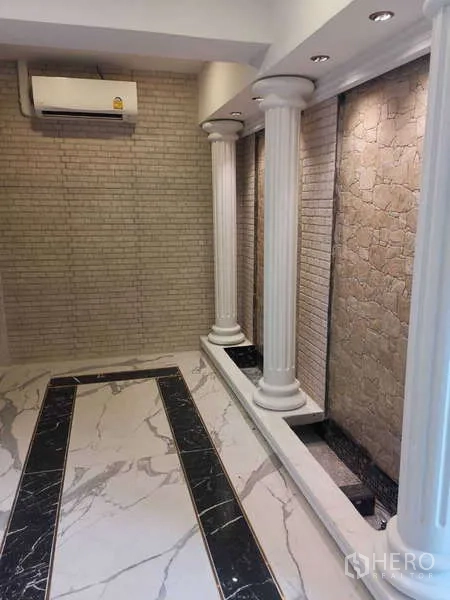 Retail Space for rent - Room with white columns, textured stone wall and marble flooring.