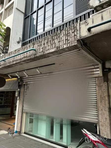 Shophouse for rent in Bang Rak, Bangkok - Shophouse frontage with metal roller shutter and glass storefront on a city sidewalk.
