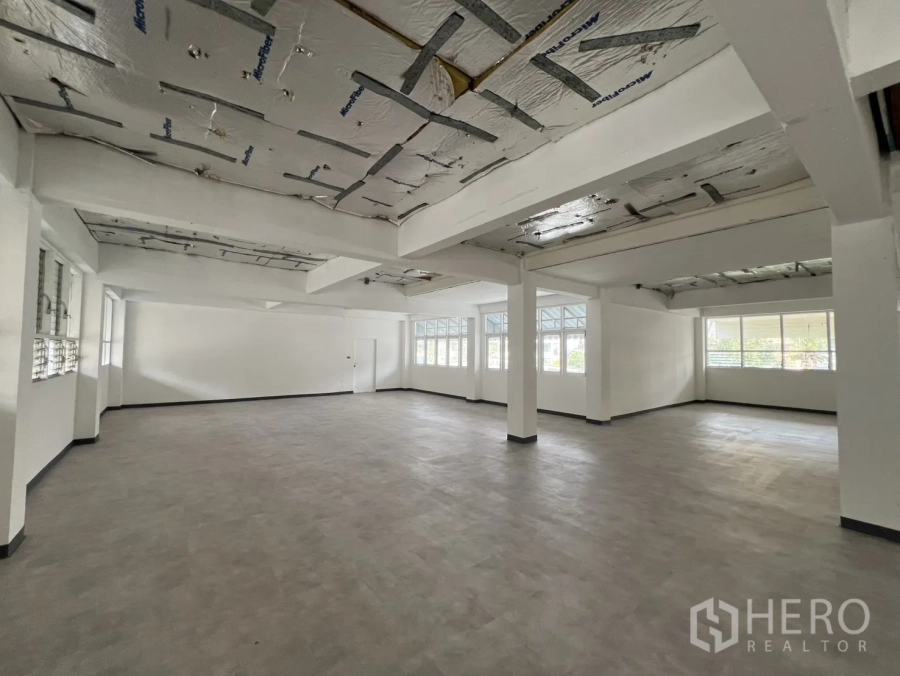 Office Space for rent in Watthana, Bangkok - Large open‑plan office floor in Sukhumvit with columns, grey flooring, and wide windows on two sides.