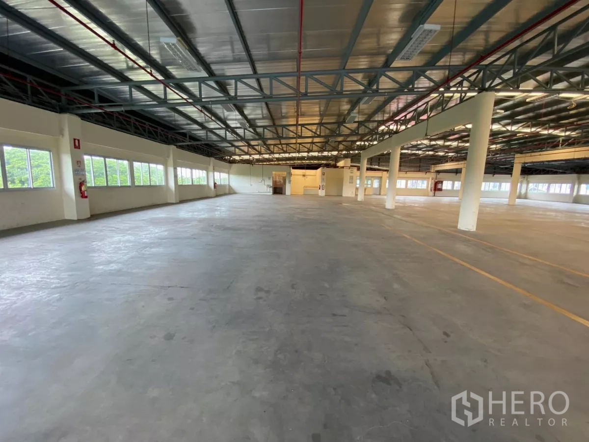 Factory for rent in Khlong Toei, Bangkok - Wide manufacturing hall with concrete floor, long windows, and marked lanes.