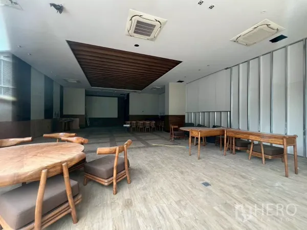 Retail Space for rent - Open-plan interior with wood-look flooring, ceiling cassette air-conditioning, and wooden tables.