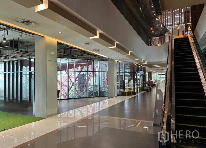 Retail Space for rent in Watthana, Bangkok - Mall corridor with an escalator beside a glass-front retail space and polished tiled floors.