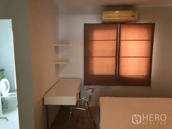 Townhouse for rent in Prawet, Bangkok - Compact bedroom with study desk, shelves, air-conditioner and ensuite door.