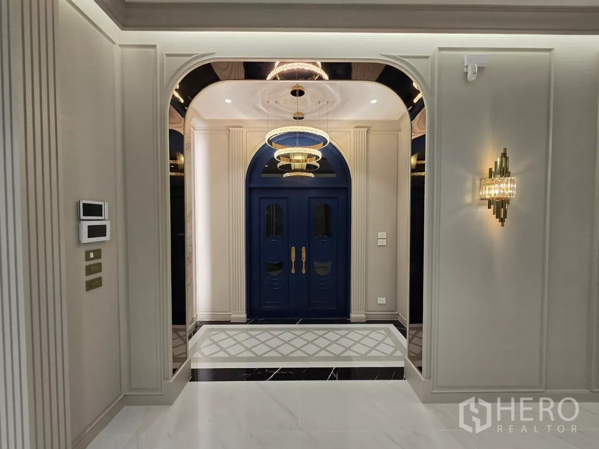 Detached House for rent or sale in Bang Kapi, Bangkok - Hallway view toward the foyer with blue doors, wall sconces and decorative moulding.